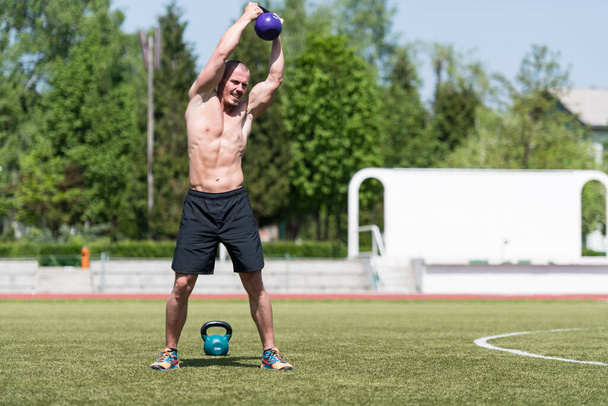 Man Working Out With Kettle Bell Outdoors - Bodybuilder Doing Heavy Weight Exercise With Kettle-bell - Photo, Image