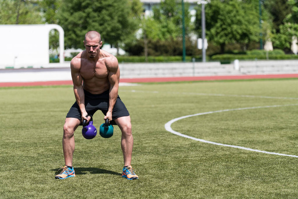 Man Working Out With Kettle Bell Outdoors - Bodybuilder Doing Heavy Weight Exercise With Kettle-bell - 写真・画像