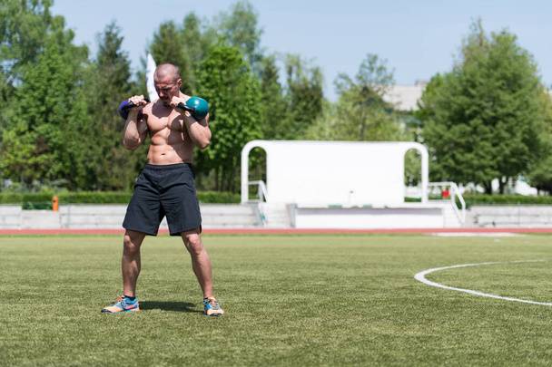 Man Working Out With Kettle Bell Outdoors - Bodybuilder Doing Heavy Weight Exercise With Kettle-bell - Photo, image