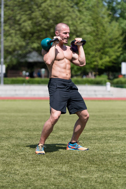 Man Exercising With Kettle Bell Outdoor and Flexing Muscles - Muscular Athletic Bodybuilder Fitness Model Exercises - Fotoğraf, Görsel