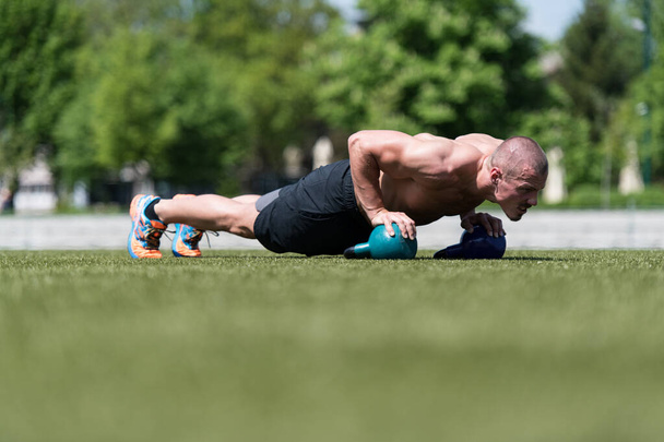 Healthy Man Athlete Doing Pushups Workout With Kettle Bell Outdoor - Kettle-bell Exercise - Fotoğraf, Görsel