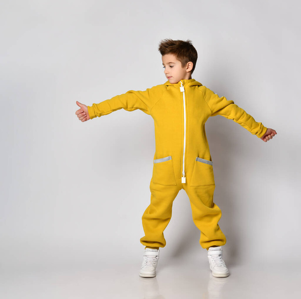 Boy in yellow sportswear showing thumbs-up looking aside - Zdjęcie, obraz