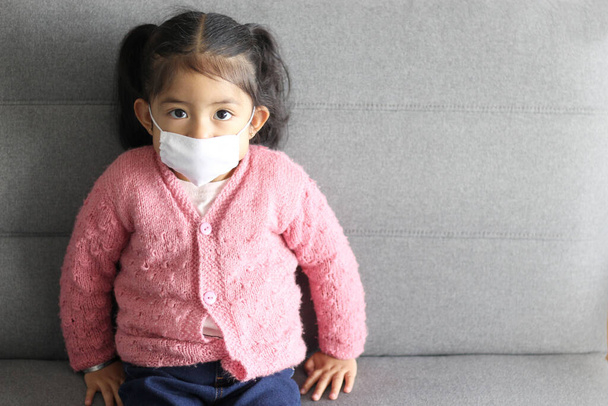 lateinisches Mädchen 2 Jahre mit Schutzmaske klinische Verwendung, um Covid-19 zu verhindern, neue normale - Foto, Bild