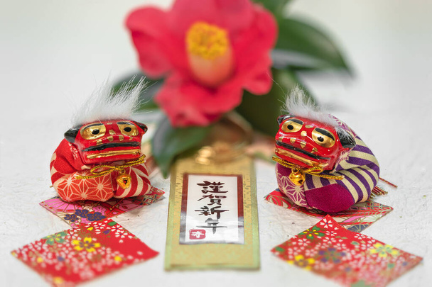 Carta di Capodanno giapponese con ideogrammi di scrittura Kingashinnen o Felice Anno Nuovo e due leoni Shishi contro un fiore di camelia tsubaki sullo sfondo. - Foto, immagini