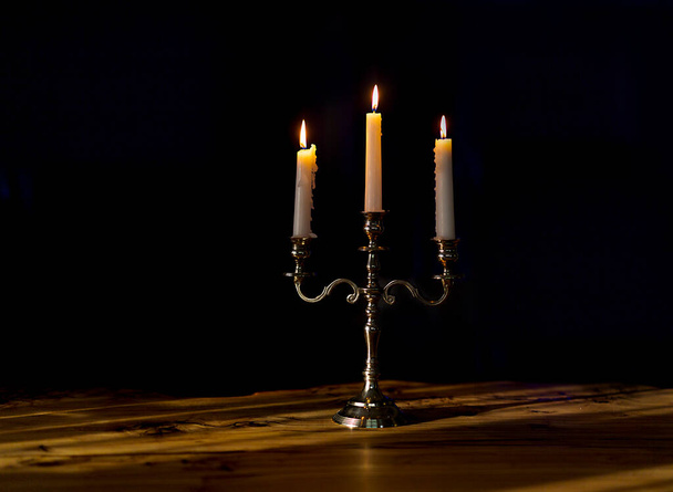 burning candles in candelabra on a black background, close-up - Foto, Imagen