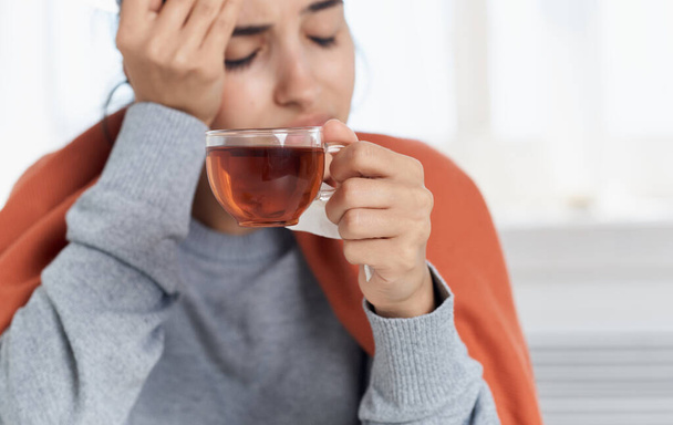 Woman with pills from hot drink indoors with orange plaid on her back - Photo, Image