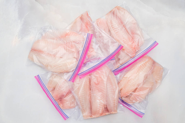 Verse rauwe visfilet in zakken met ritssluiting. Tilapia filet op licht marmeren achtergrond, van bovenaf gezien - Foto, afbeelding