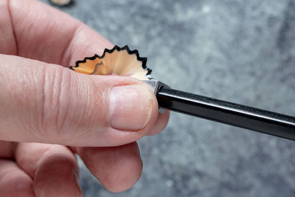 Mãos realizando a ação de afiar um lápis com um apontador de lápis padrão. - Foto, Imagem