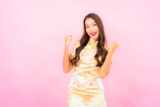 Retrato hermosa joven mujer asiática sonrisa en acción con el concepto de año nuevo chino sobre fondo de color rosa - Foto, Imagen