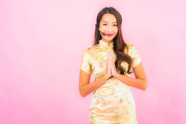 Retrato hermosa joven asiática mujer atención al cliente centro de llamadas en color rosa fondo - Foto, imagen
