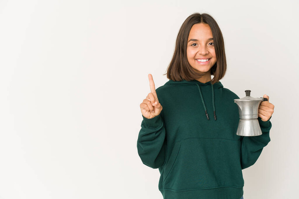 jonge latino vrouw met een koffiezetapparaat tonen nummer een met de vinger. - Foto, afbeelding