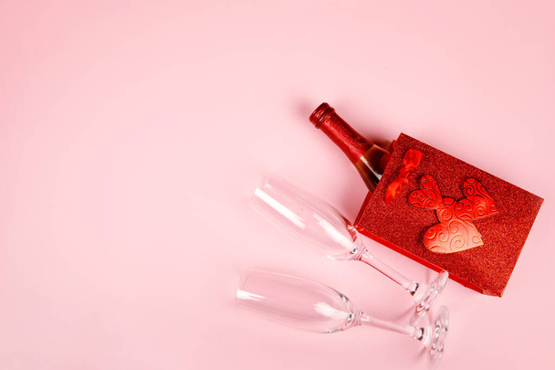 Feliz San Valentín flatlay. Botella vista superior de champán rosa en caja de regalo, corazones, vasos sobre fondo rosa suave. Tarjeta de felicitación de San Valentín o Año Nuevo - Foto, Imagen
