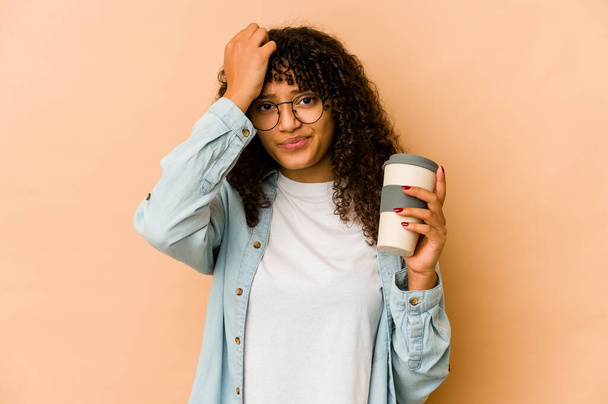 Young african american afro woman holding a takeaway coffee being shocked, she has remembered important meeting. - Foto, Imagem