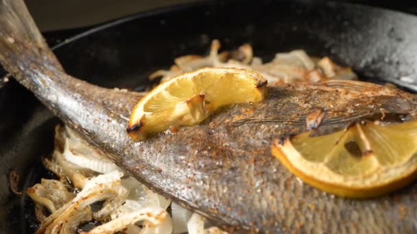 Panela com peixe dorada frito em fatias de cebola e limão em cima - Filmagem, Vídeo