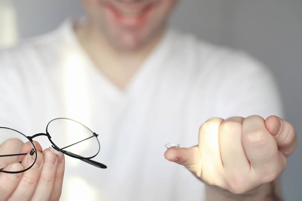 El concepto de mala visión. Sostenga una lente de contacto y gafas en la mano. Póster para gafas y lentes publicitarias. - Foto, imagen