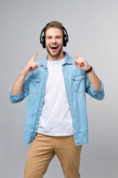 Close up portrait of cheerful young man enjoying listening to music wearing casual jeans outfit - Foto, Imagem