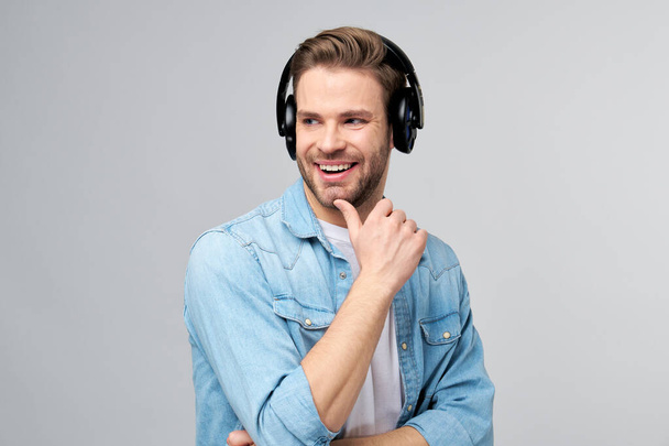 Close up portrait of cheerful young man enjoying listening to music wearing casual jeans outfit - Фото, зображення