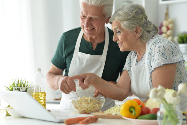 happy senior couple making salad together at kitchen - Фото, зображення