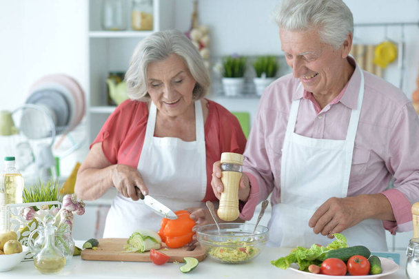 Senior couple making salad together at kitchen - Фото, зображення