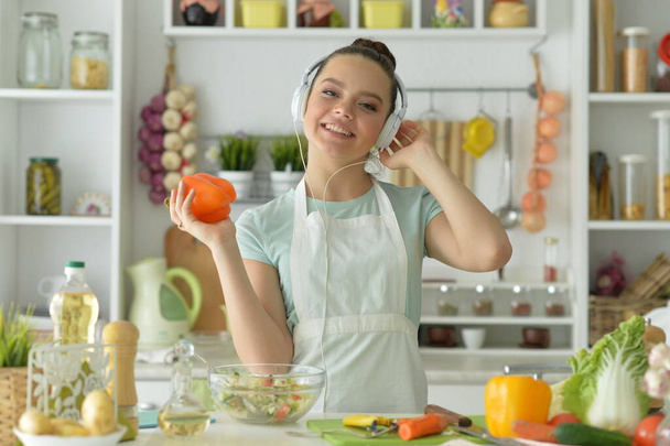 beautiful young woman making  salad  and listening to music  - Photo, image