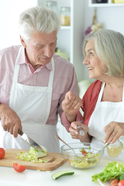 Senior couple making salad together at kitchen - Photo, image