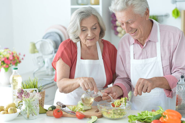 Senior couple making salad together at kitchen - Photo, Image