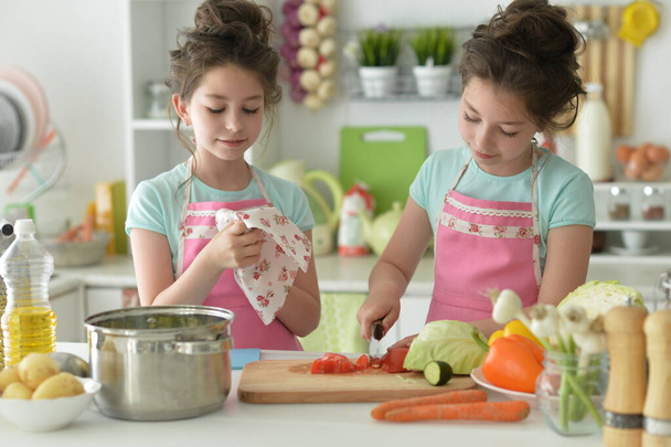 Cute girls preparing delicious fresh salad in kitchen - Foto, imagen