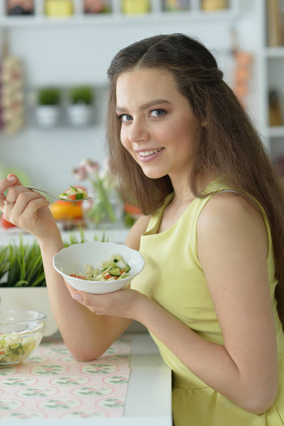 beautiful young woman eating  salad   in kitchen - Foto, Bild