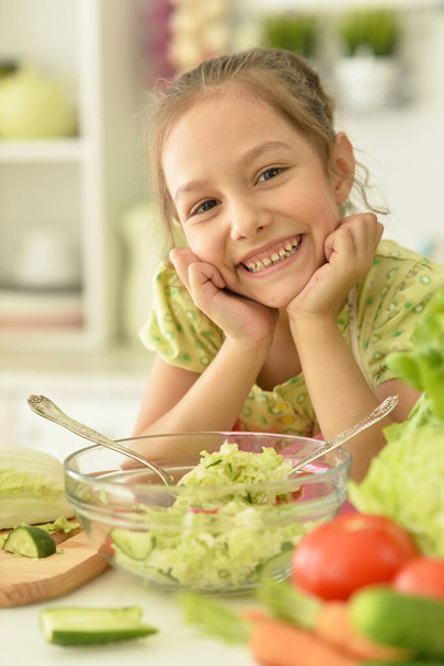 Cute girl preparing delicious fresh salad in kitchen - Zdjęcie, obraz
