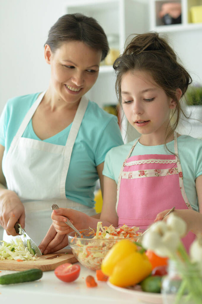 Cute little girl with her mother cooking   together at kitchen table  - Foto, Imagen