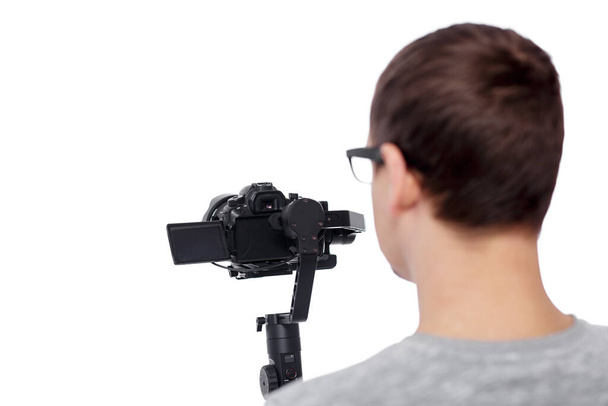 visão traseira de vídeo de filmagem de videógrafo profissional com câmera dslr no estabilizador gimbal isolado no fundo branco - Foto, Imagem