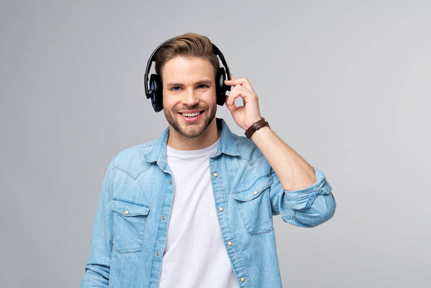 Close up portrait of cheerful young man enjoying listening to music wearing casual jeans outfit - Photo, Image