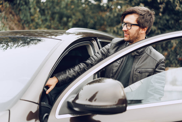 Stylish man in glasses sits in a car - Foto, afbeelding