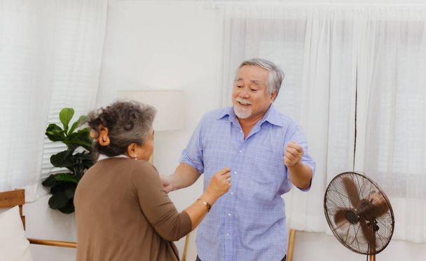 Aziatisch gelukkig gepensioneerd senior glimlachend schattig ouder paar genieten & lachen samen dansen in huis. Romantische relatie van mooie & mooie huwelijksliefde met geluk levensstijl na pensionering - Foto, afbeelding