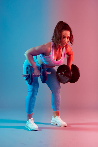 Confident plus size young woman working out fitness exercises, dual tone blue red - 写真・画像