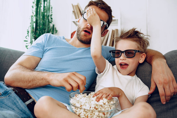 Father and son watching movies at home in 3d glasses and eating popcorn - Foto, Bild