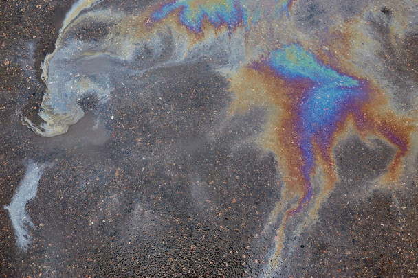 Színes olajfoltok a parkolóban, a szín a benzin folt a járdán, mint a háttér.Absztrakt szivárvány hatás háttér - Fotó, kép