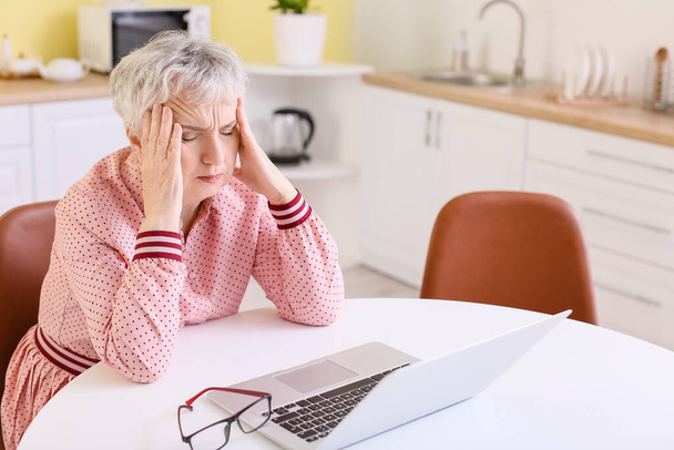 Gestresste Seniorin leidet zu Hause unter Kopfschmerzen - Foto, Bild