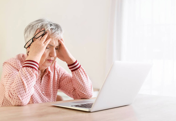 Evde baş ağrısı çeken stresli yaşlı kadın. - Fotoğraf, Görsel