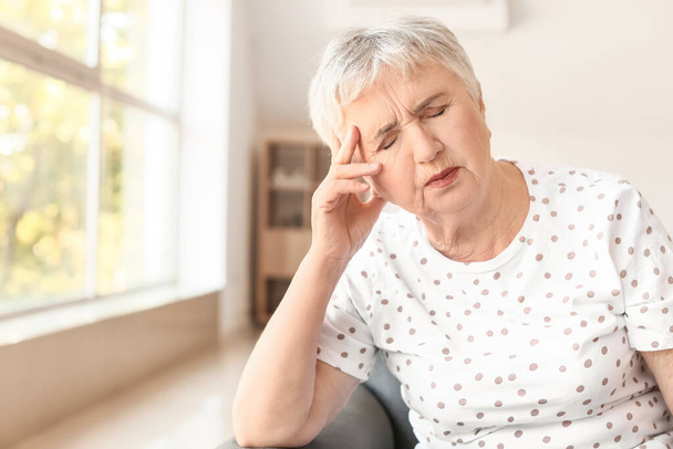 Gestresste Seniorin leidet zu Hause unter Kopfschmerzen - Foto, Bild