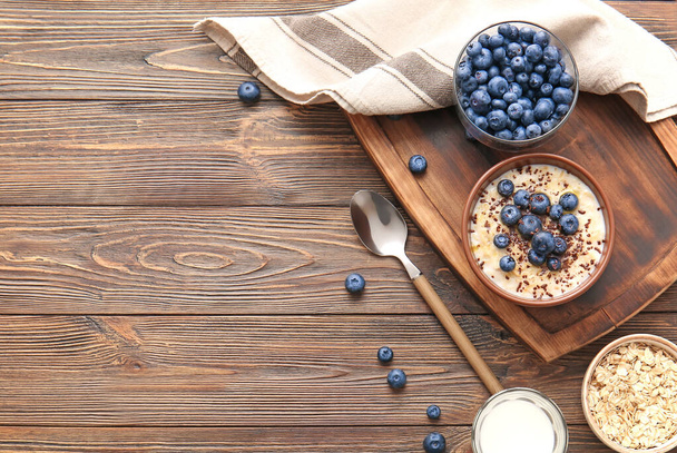 Bowl with tasty oatmeal and blueberry on wooden table - Фото, изображение