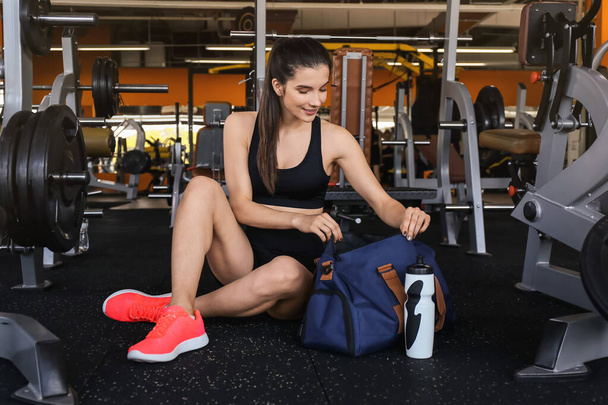 Jeune femme avec sac de sport dans la salle de gym - Photo, image