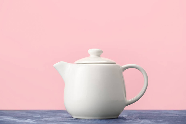 Teapot on table against color background - Fotoğraf, Görsel