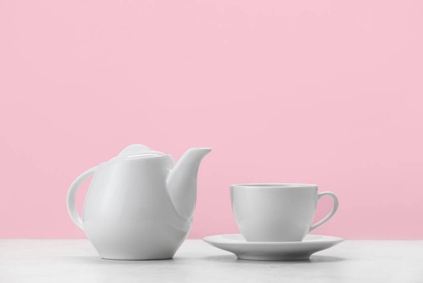 Teiera e tazza sul tavolo contro lo sfondo di colore - Foto, immagini