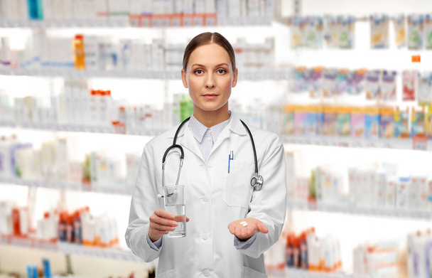 doctor with pills and glass of water at pharmacy - Фото, изображение