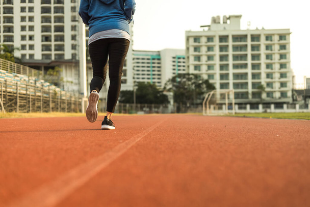 Young woman running on track race at sport stadium in the city. - Valokuva, kuva