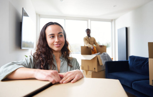 Portrait of young mixed ethnicity couple standing in lounge of new home unpacking removal boxes together - Photo, Image