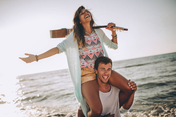 Молодой человек катается на спине с подружкой на пляже. - Фото, изображение