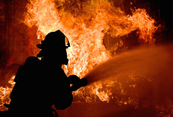 Η σιλουέτα των πυροσβεστών που πολεμούν μια μαινόμενη φωτιά με φλόγες. Πυρκαγιά. - Φωτογραφία, εικόνα