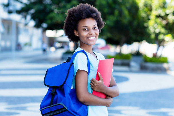 Laughing african american female student in city walking to university in summer - Photo, Image